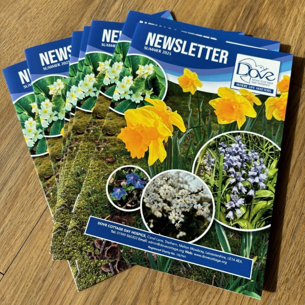 Printed Dove Cottage newsletter copies on a wooden table