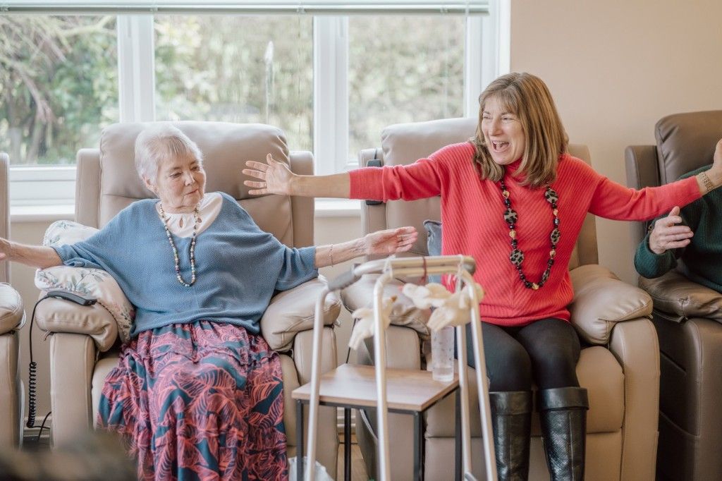 Two women enjoying a wellbeing activity together in a bright day hospice lounge