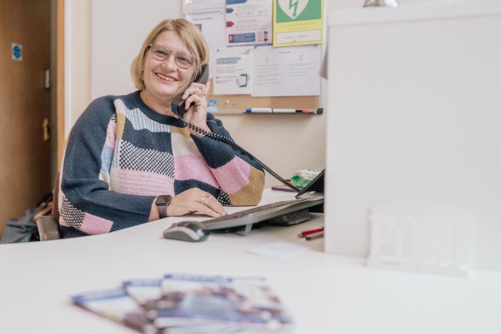 Team member smiling while answering the phone at reception desk