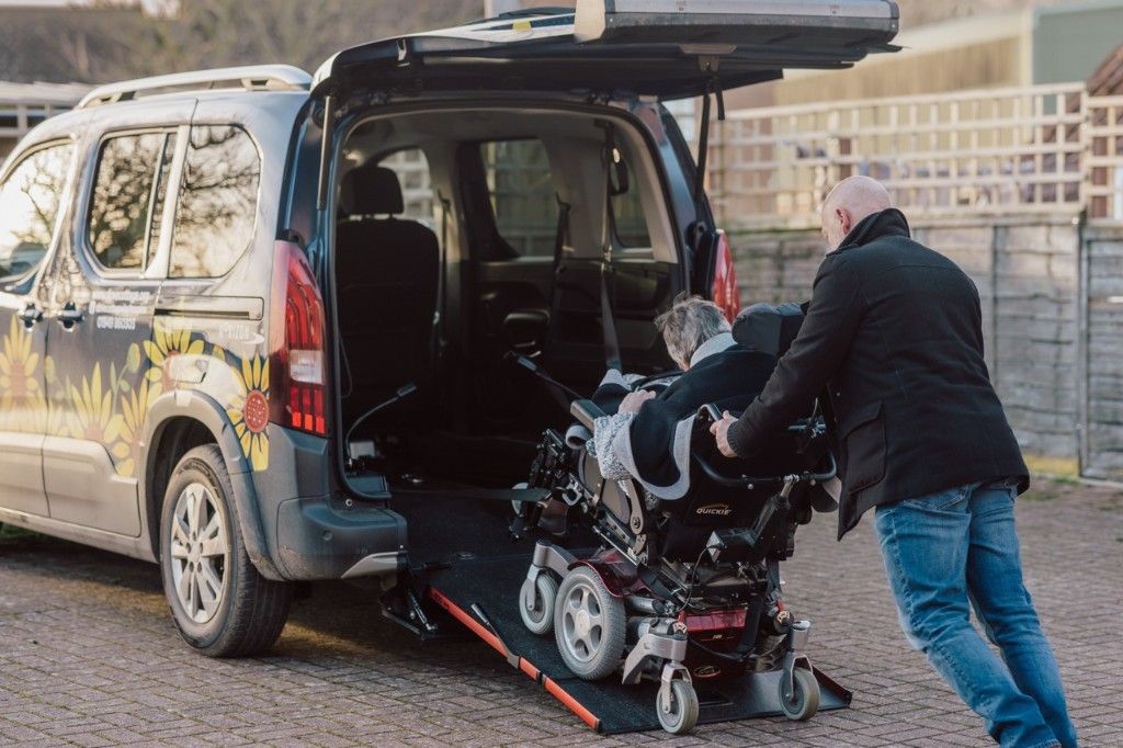A volunteer assisting a wheelchair user into a Dove Cottage accessible vehicle