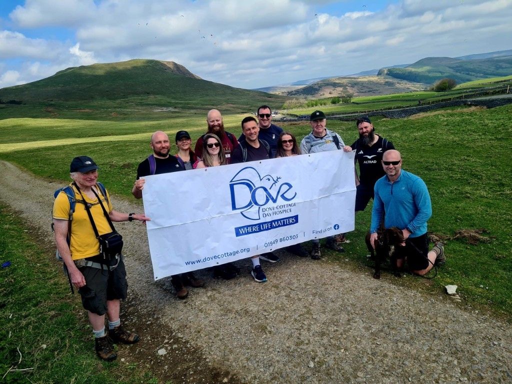 Group of Dove Cottage supporters holding a fundraising banner in the countryside
