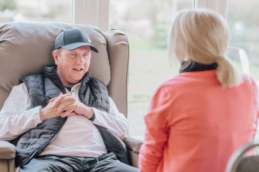 A patient speaking with a bereavement support team member in a calm hospice setting